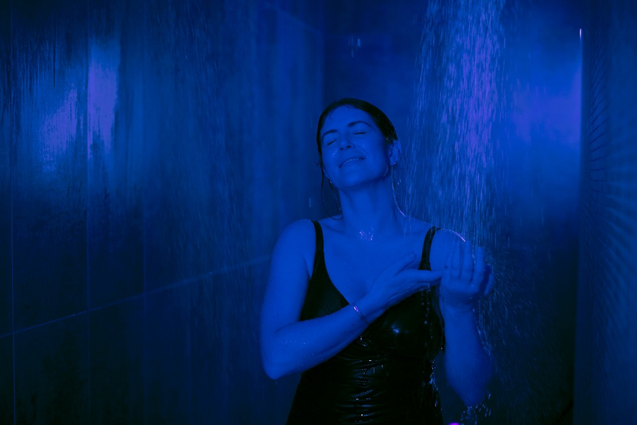 Woman standing in a Rain Walk Shower holding her hands under the flowing water.